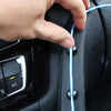 Eine Hand justiert ein blaues Kabel mit schwarzen Befestigungsclips auf einer Auto-Innenausstattung.