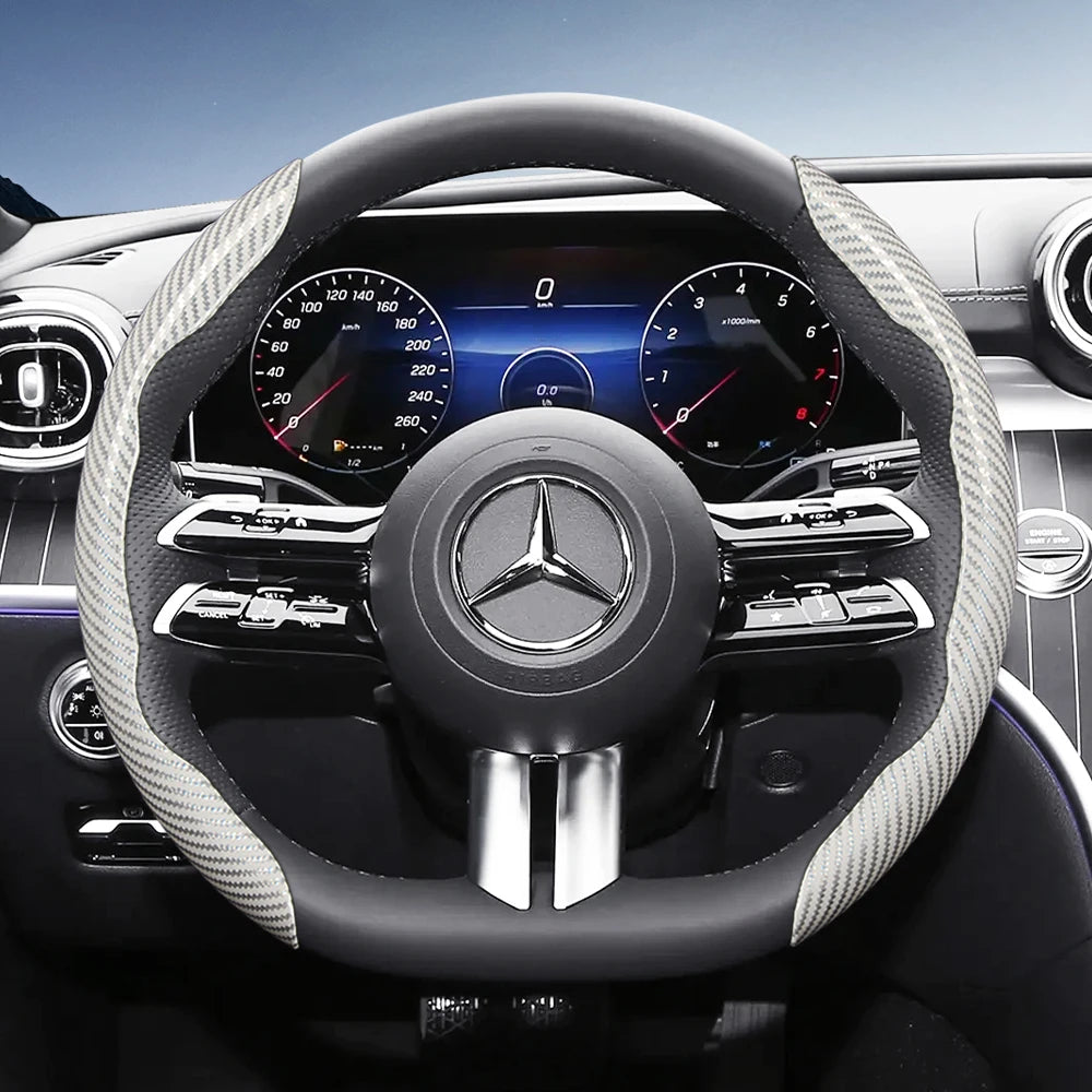 Close-up view of a black steering wheel with carbon fiber texture grips and a central Mercedes logo.