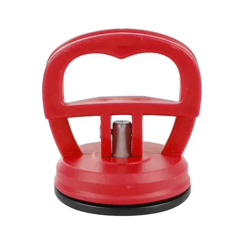 Outil tire-bosses avec ventouse lourde rouge, poignée et base en caoutchouc.