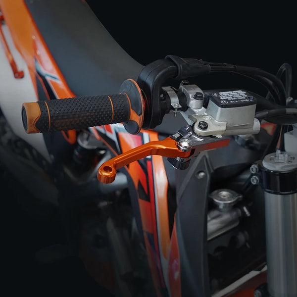 Close-up of precision aluminum brake and clutch levers mounted on an orange off-road motorcycle frame.
