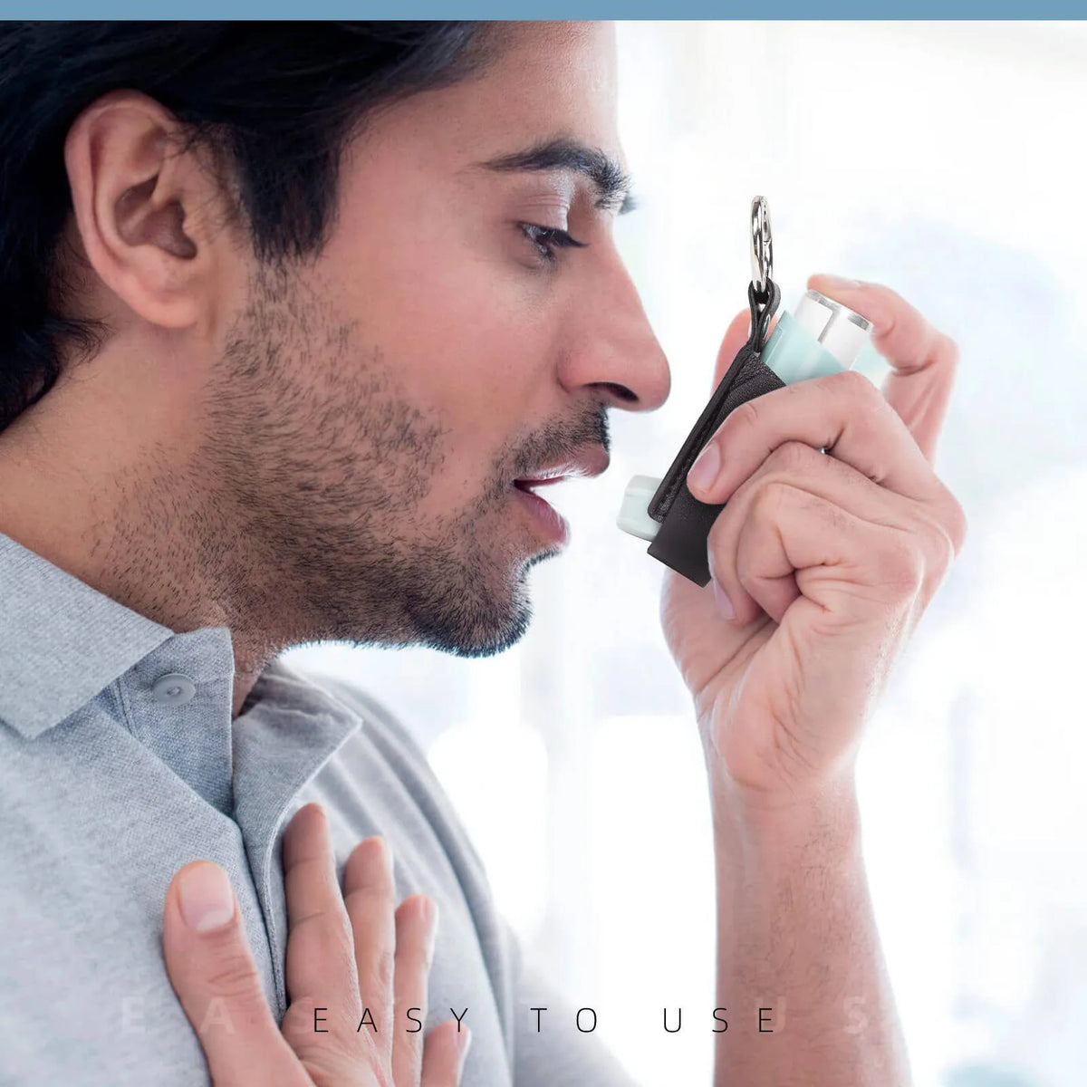 A man is holding a portable inhaler storage case with a keychain, preparing to use it.