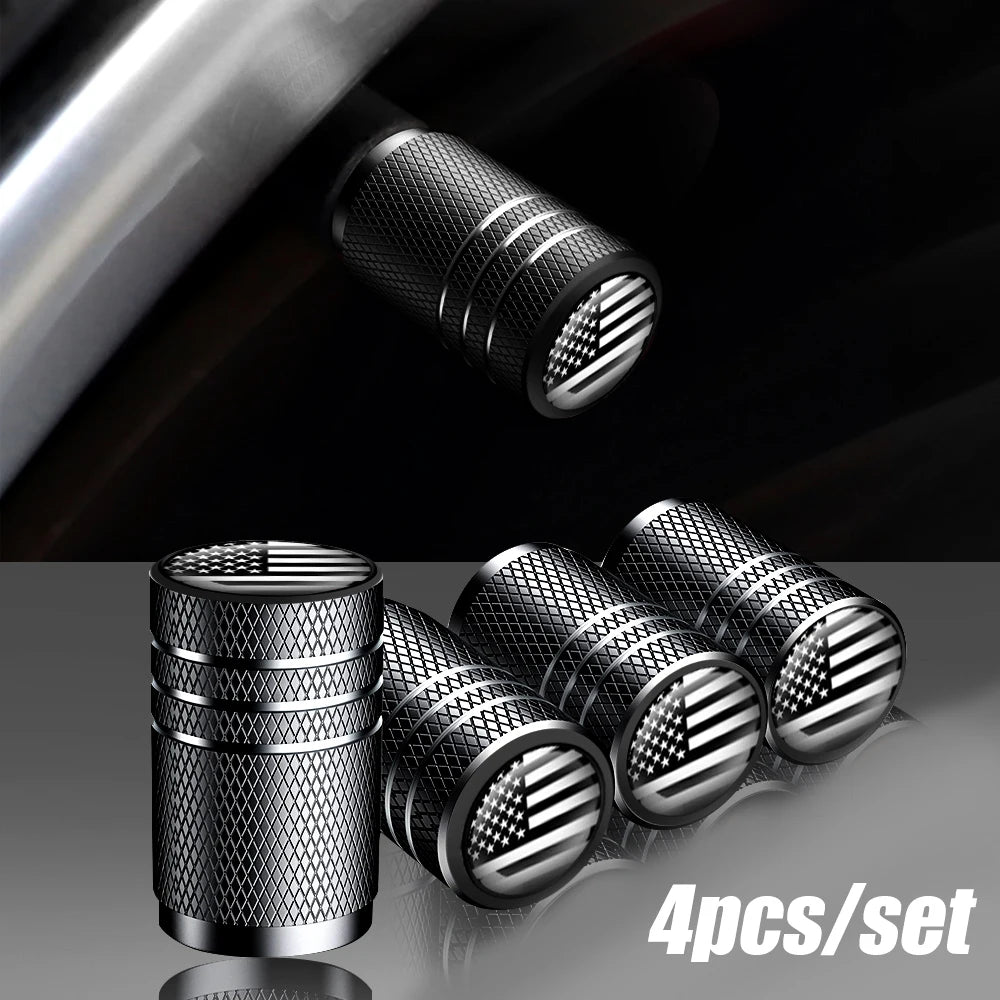 A set of four American flag aluminum tire valve caps shown in close-up against a dark background.