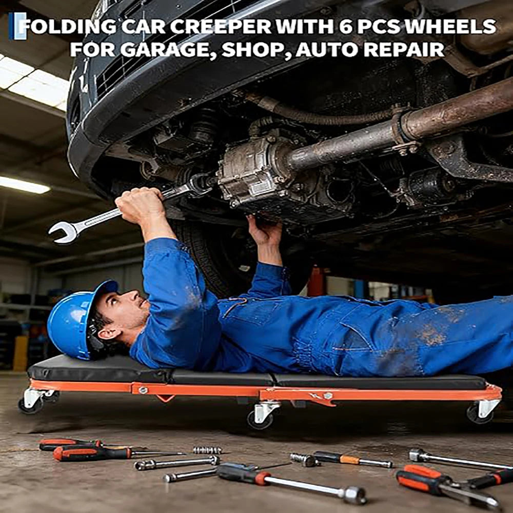 A mechanic in a blue jumpsuit is using a folding car creeper with six wheels under a car in a garage setting.