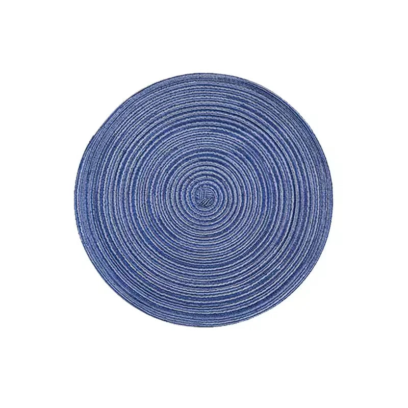 A round placemat made of blue-gray yarn with concentric circular stripes.