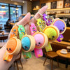 A hand holds several colorful silicone keychains shaped like bao buns with various pastel colors and charms.