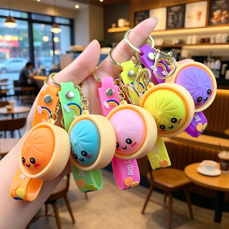 A hand holds several colorful silicone keychains shaped like cute bao buns with various charms.