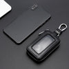 A black leather car key protector pouch with a metal clasp is shown next to a smartphone.