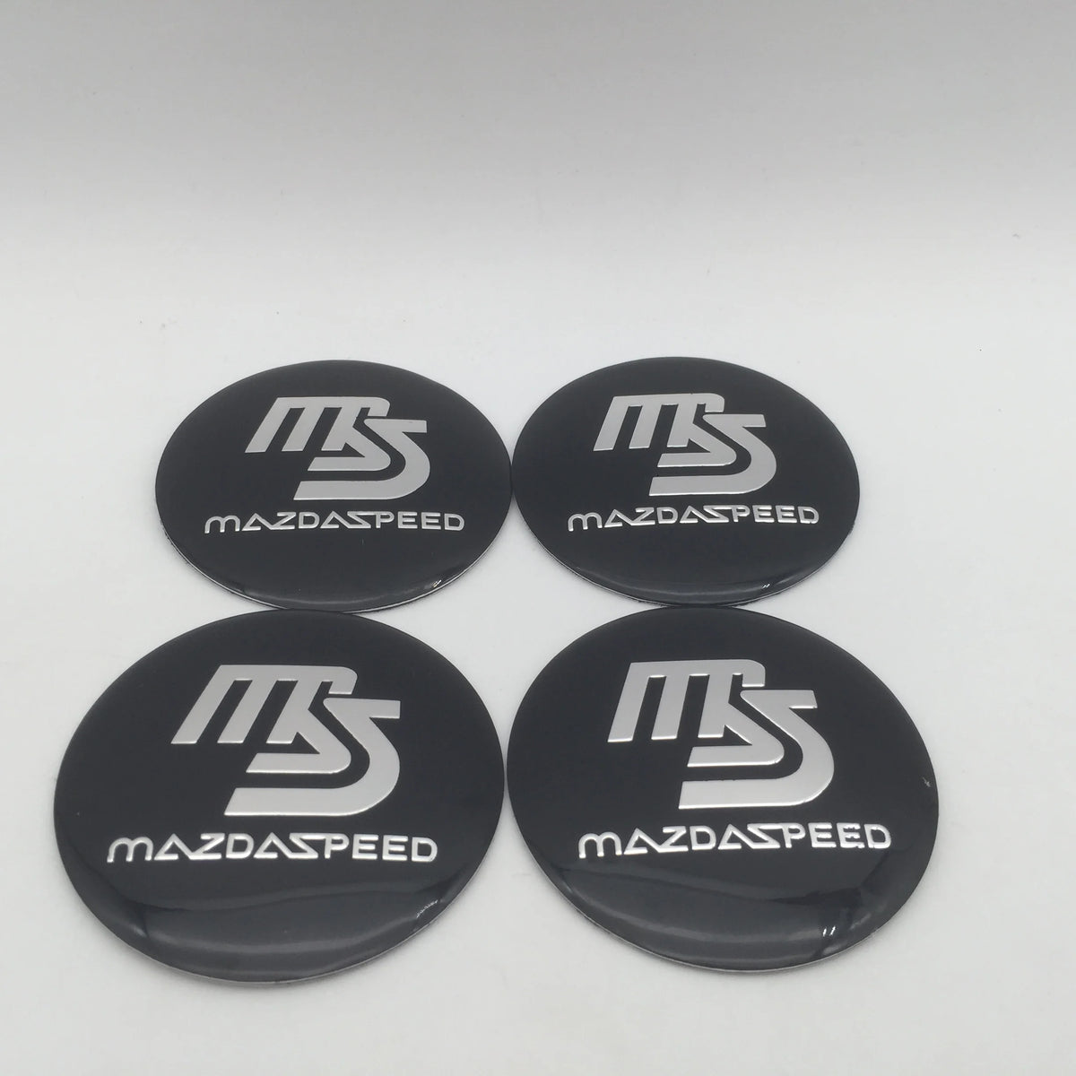 Four black center caps with silver MS logos for Mazda speed car wheels