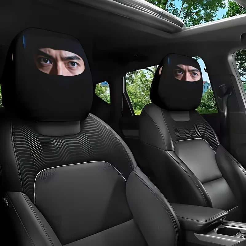 Two black car seat headrest covers with mysterious eye print designs installed in a vehicle interior.