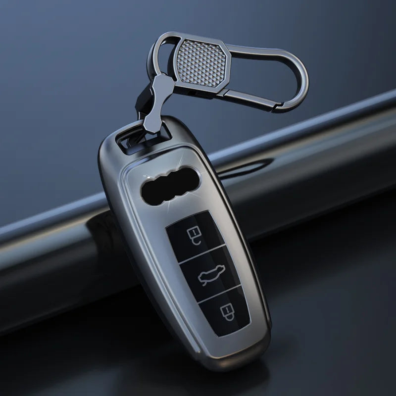 A silver leather car key case cover with a metal loop is shown against a dark background.