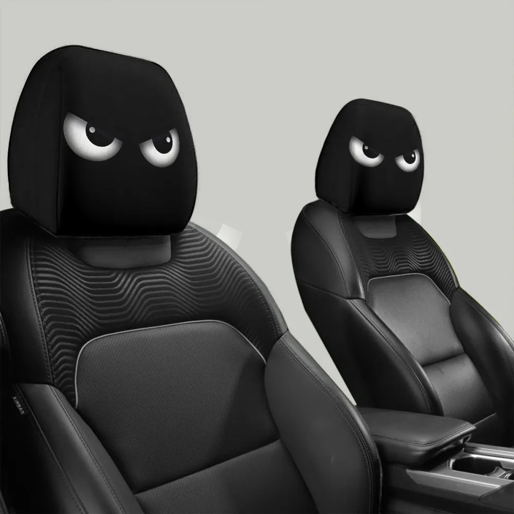 A pair of black car headrest covers with slanted eyes are shown in a close-up view.