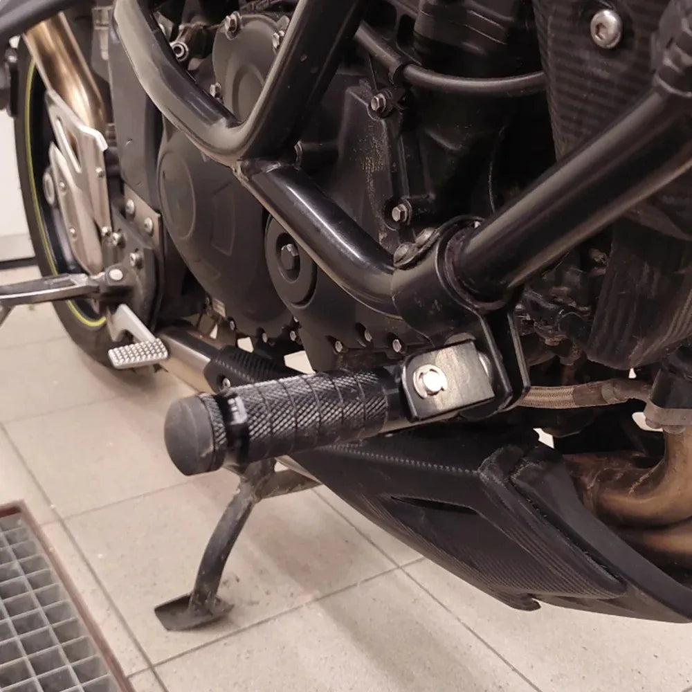 Close-up view of black universal motorcycle foot pegs and footrests mounted on a bike frame.