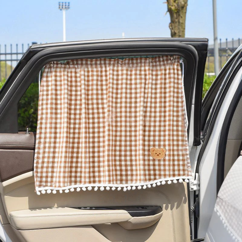 Un parasol a cuadros marrón y blanco está instalado en la ventana trasera de un coche.