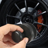 Une main tient un kit de brosse de detailing noir placé dans un jante de voiture.