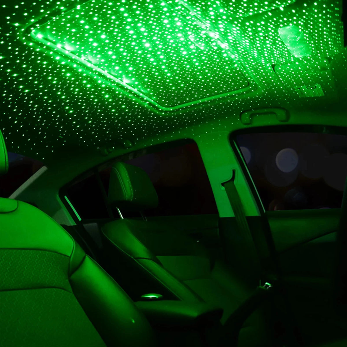 Vue intérieure d'une voiture avec un projecteur ciel étoilé LED vert vif illuminant le plafond et l'habitacle.