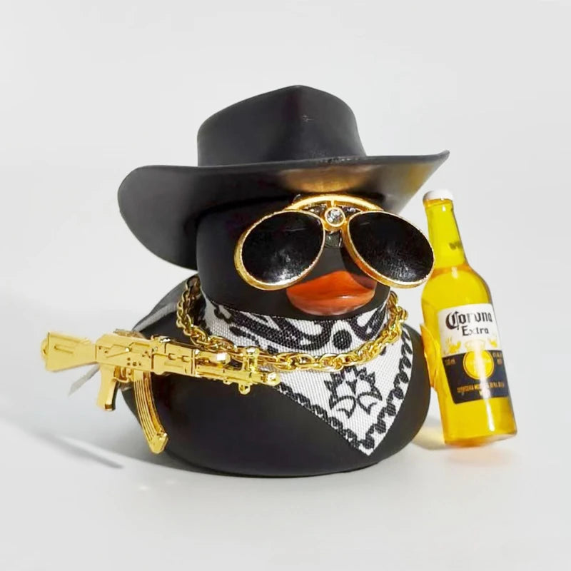 A black rubber duck car ornament wearing a wide-brimmed hat and sunglasses, with a gold chain and a yellow bottle in the back