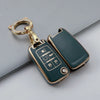 A gold-toned key fob case with a textured green finish and a loop attached, resting on a gray surface.