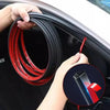 A hand is holding a coil of red and black rubber weather stripping for car door seals.