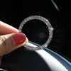 A hand holds a circular ring of clear stones, which is a decorative ignition push button cover for a car.