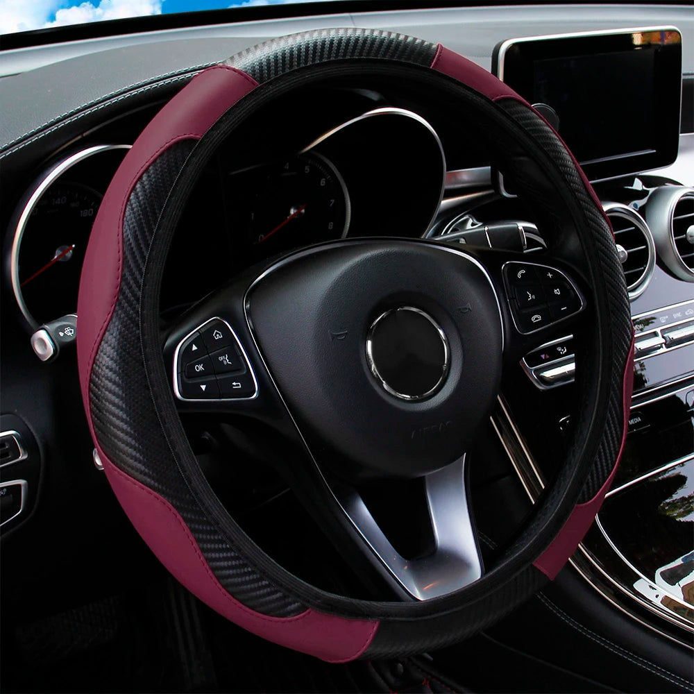 A close-up view of a black steering wheel with a maroon PU carbon fiber cover inside a car interior.