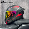 Casque de moto modulaire noir et rouge DOT avec une visière teintée posé sur une surface en cuir noir.