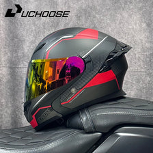 A black and red modular DOT motorcycle helmet with a tinted visor resting on a black leather surface.