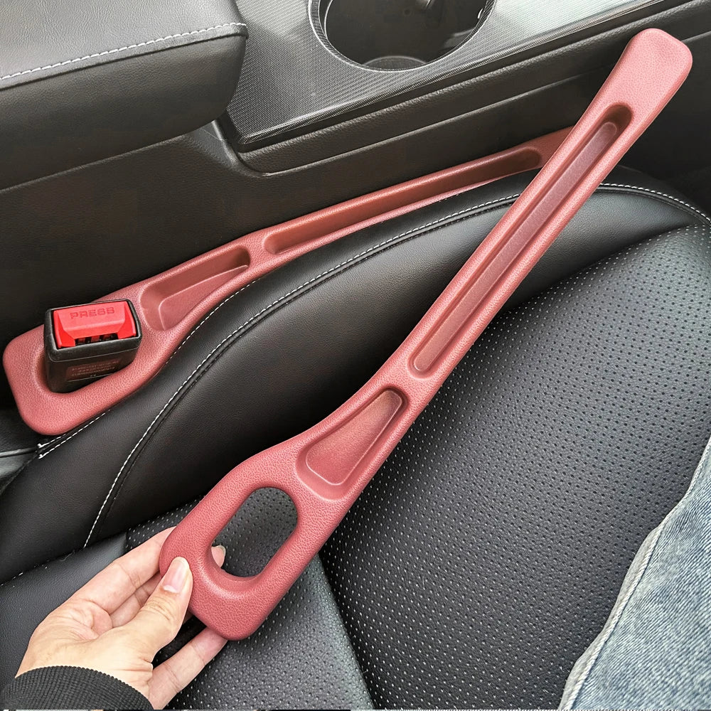 A hand holds a pink car seat gap filler strip designed to fill gaps in a vehicle seat.