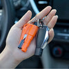 A hand holds an orange emergency car escape tool with a window breaker and seatbelt cutter.
