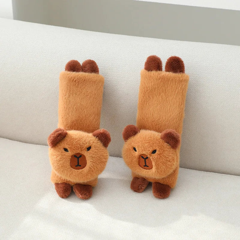 A pair of fluffy, orange plush capybara-shaped neck pillows resting on a white surface.