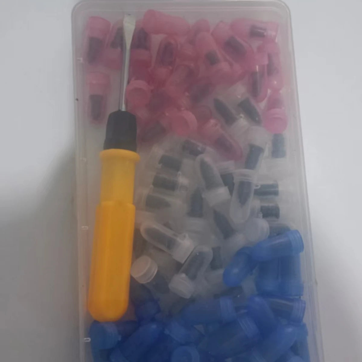 A clear plastic container filled with various colored rubber components for a universal tire repair kit