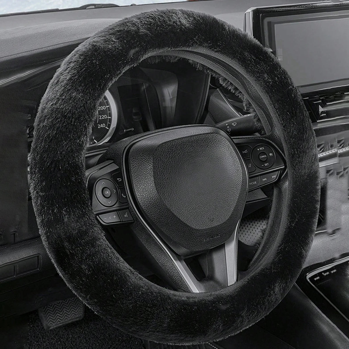 A close-up view of a black winter plush steering wheel cover inside a car interior.