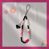 A black lanyard with a round bead pendant featuring pink, white, and black beads and a heart charm.
