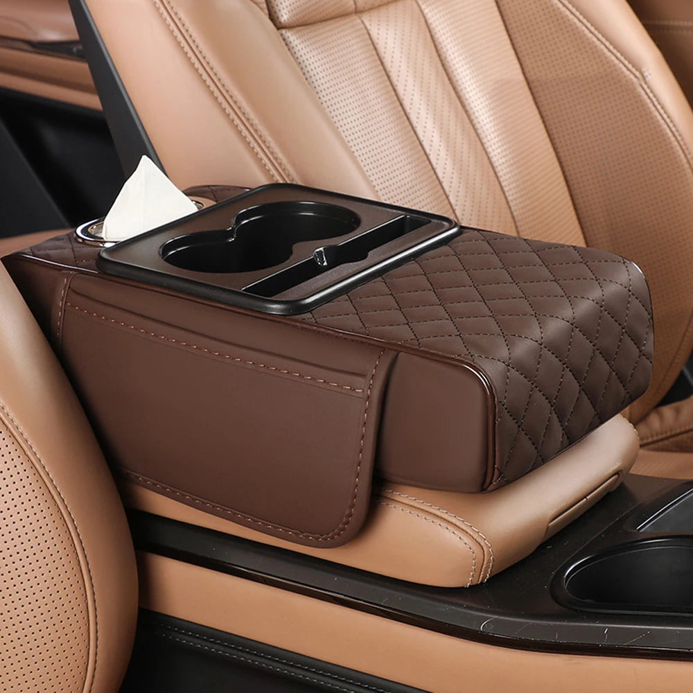 A brown quilted car armrest cushion with a tissue holder is placed on a tan leather seat.