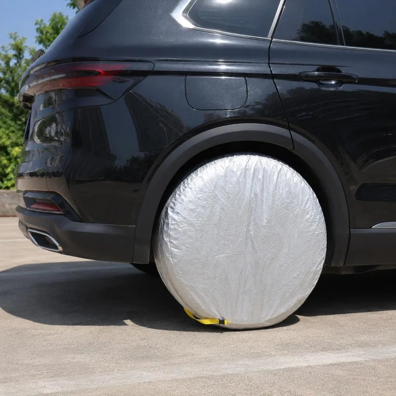 A black SUV tire is covered with a silver plastic storage cover on the wheel well.