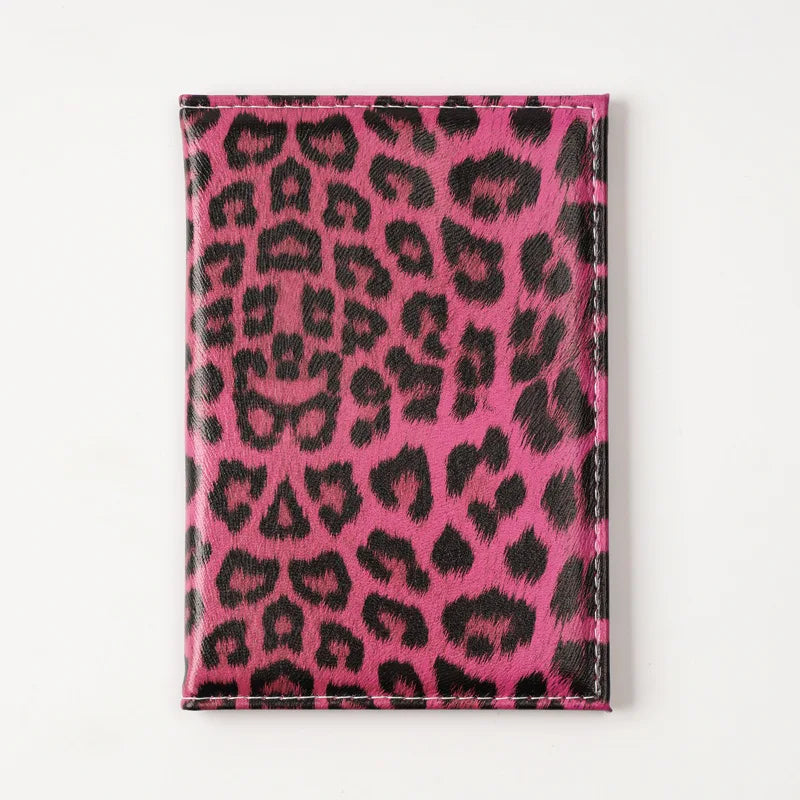 A vibrant pink leopard print passport holder with card slots.