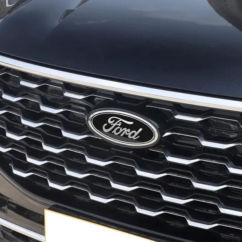 Close-up of a black car's grille featuring the Ford emblem badge.