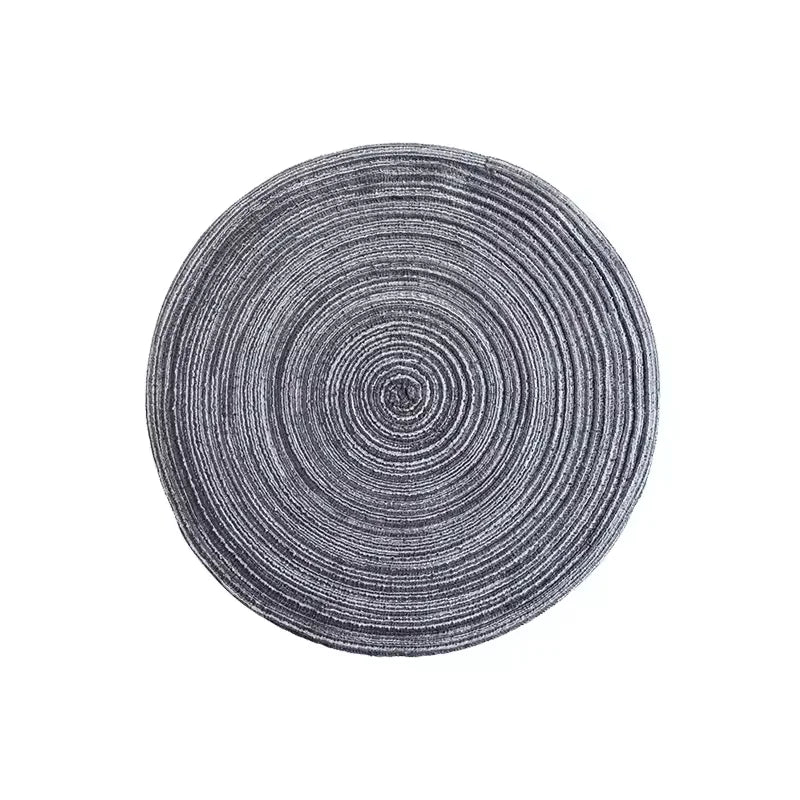 A round placemat made of gray, textured cotton yarn with concentric circular lines.