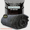 A black microfiber car drying towel rolled up, with a bag labeled absorb up to one gallon of water.