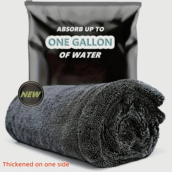 A black microfiber car drying towel rolled up, with a bag labeled absorb up to one gallon of water.