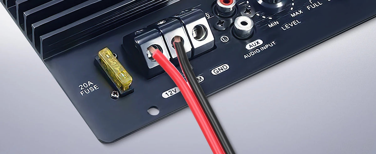 A close-up view of a dark electronic device showing terminals, a fuse holder, and an audio input jack.
