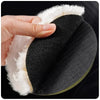 A hand is holding a black wool buffing pad with white fur trim for car polishing and detailing.