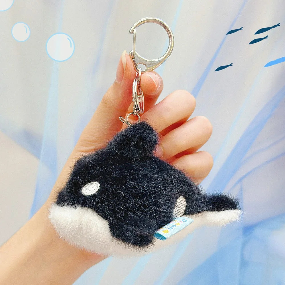 A hand holds a black and white plush bunny keychain with soft fur attached to a gold ring.