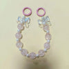 A pink and white beaded lanyard featuring a round bead pendant and a floral charm.