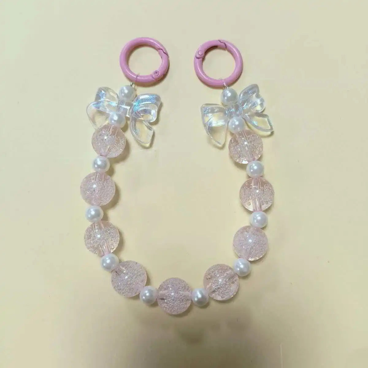A pink and white beaded lanyard featuring a round bead pendant and a floral charm.