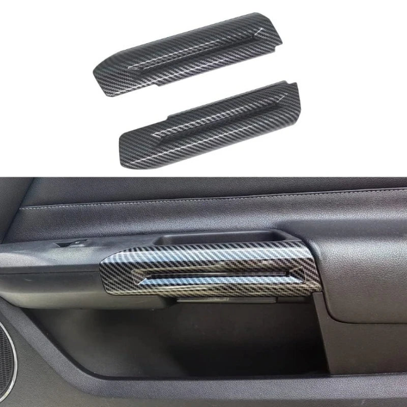 Black carbon fiber trim piece for a car interior door handle.