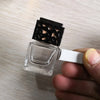 A clear glass car air freshener bottle with a black mesh top is held in a hand.