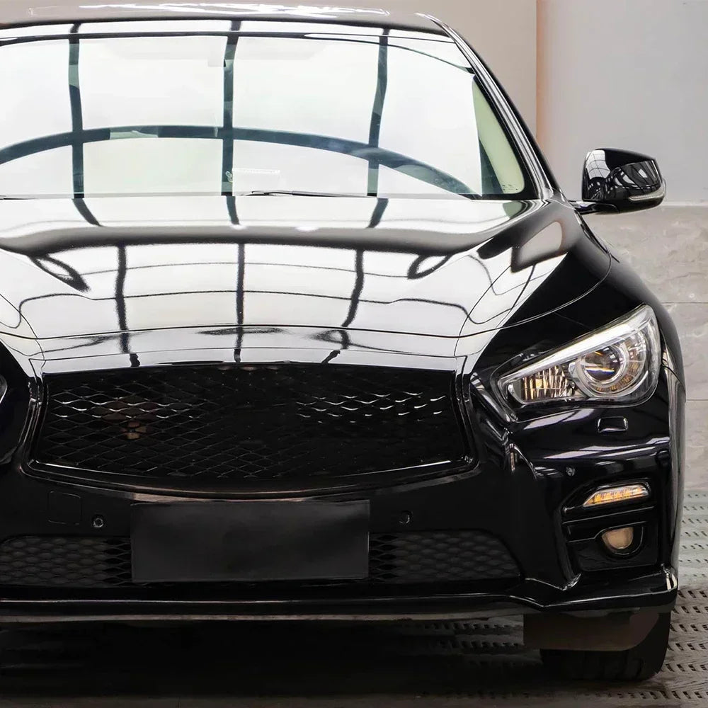 Close-up of a glossy black car featuring aftermarket front grille and headlight modifications.
