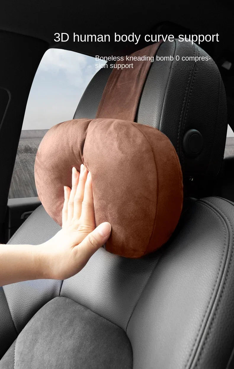 Une main repose sur un support de nuque rembourré marron posé sur un dossier de voiture noir.