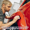 A man is using a felt squeegee tool to remove bubbles and minimize scratches from a red car's vinyl surface.