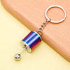A silver keychain with a colorful, iridescent cylindrical charm attached to a split ring.